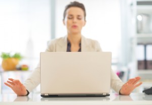 Closeup on laptop and relaxing business woman in background